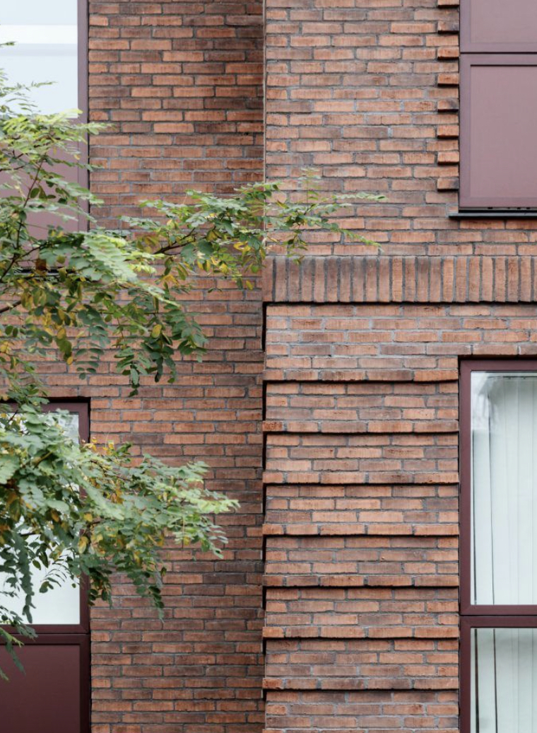 Detail van een metselwerkgevel met groen ervoor